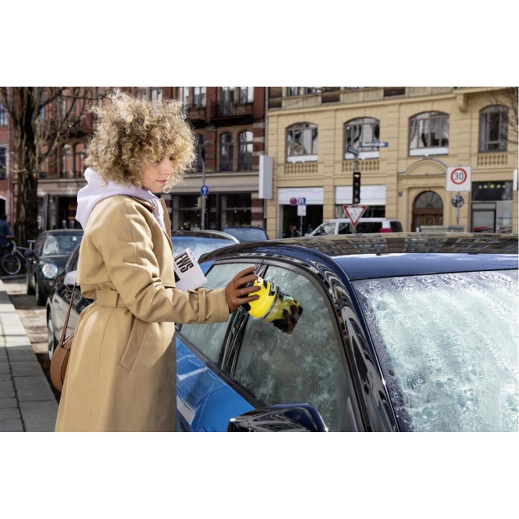 Person befreit Autoscheibe von Eis mit Eiskratzer.