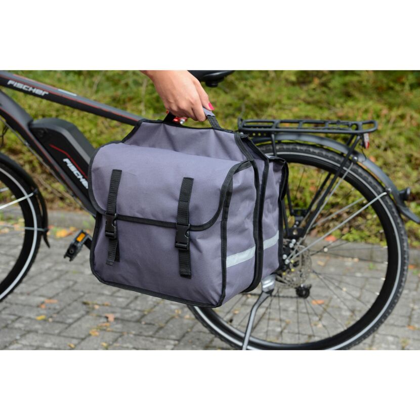 Person hält graue Gepäckträgertasche am Griff