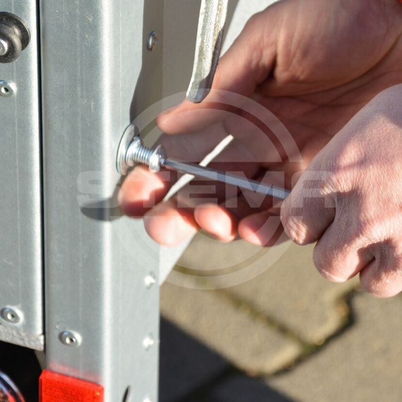 Person schraubt mit Schraubendreher an Anhänger.