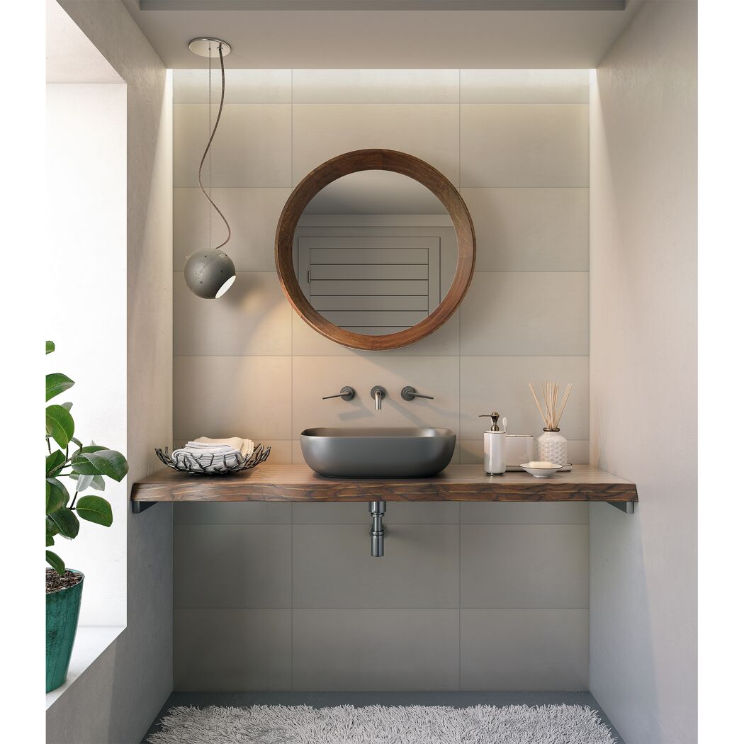 Modernes Badezimmer mit rundem Spiegel und grauen Waschbecken.