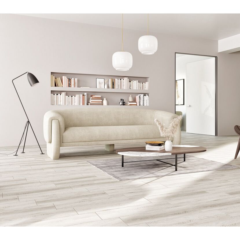 Wohnzimmer mit hellem Sofa, Bücherregal, Couchtisch und Stehlampe