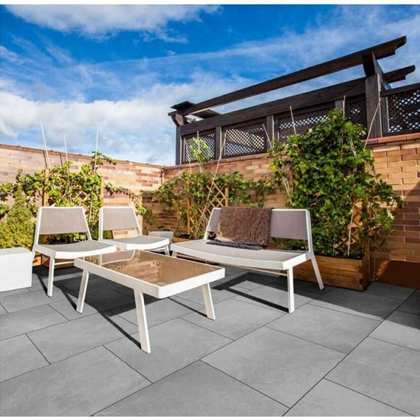 Gepflasterte Terrasse mit Gartenmöbeln und Pflanzenkübeln