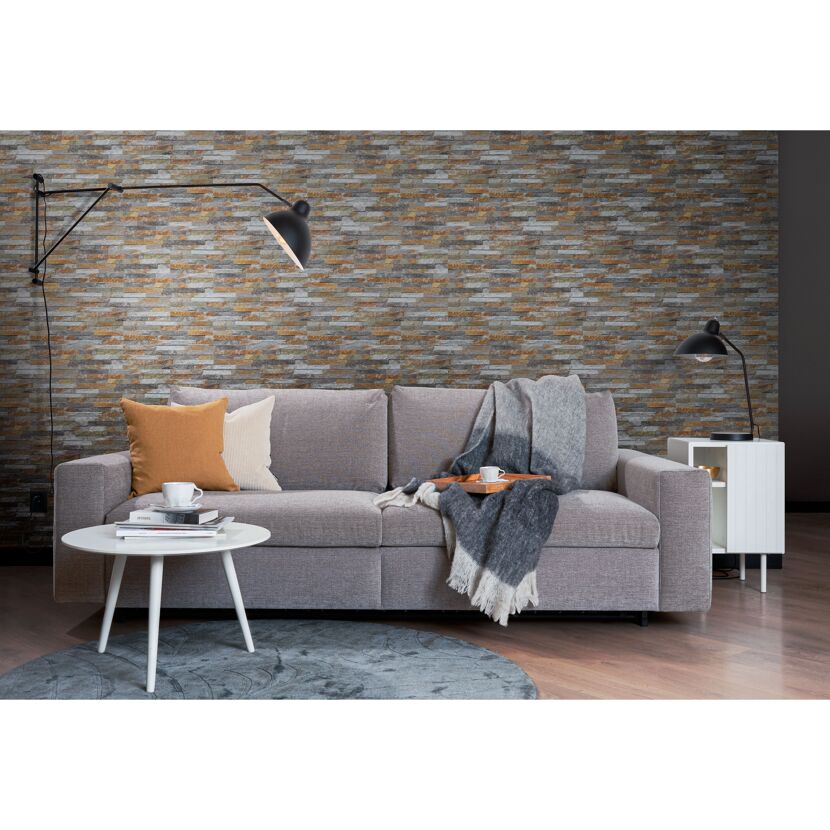 Graues Sofa vor Steinwand