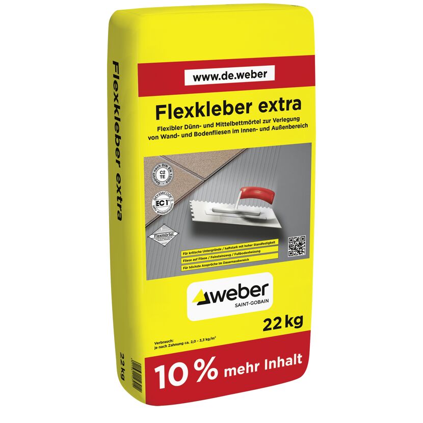 Flexkleber in Sack, dahinter Fliesen und Zahnspachtel