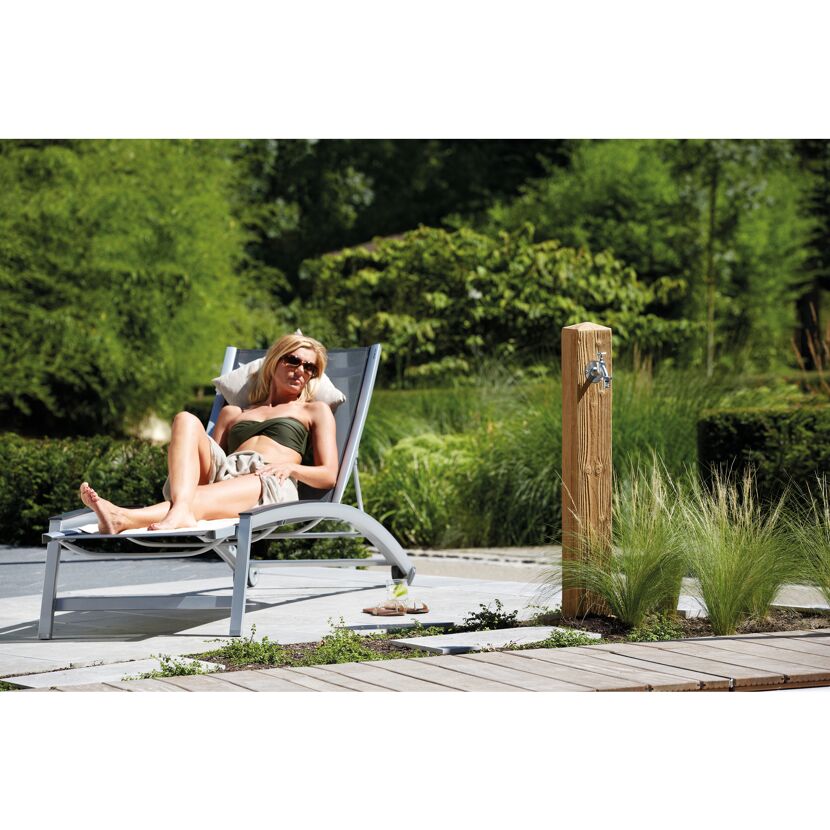 Person entspannt auf Gartenliege neben Wasserzapfsäule