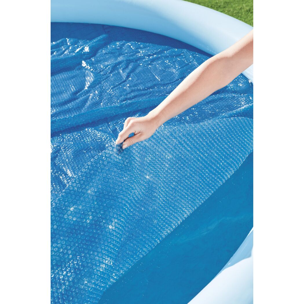 Person deckt einen Pool mit einer blauen Solarplane ab.