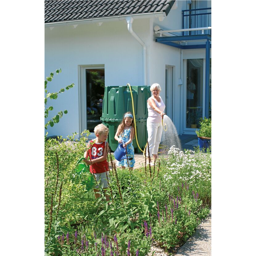 Personen gießen mit Gießkanne und Gartenschlauch Pflanzen im Garten.