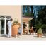 Familie entspannt auf der Terrasse am Haus mit Regentonne