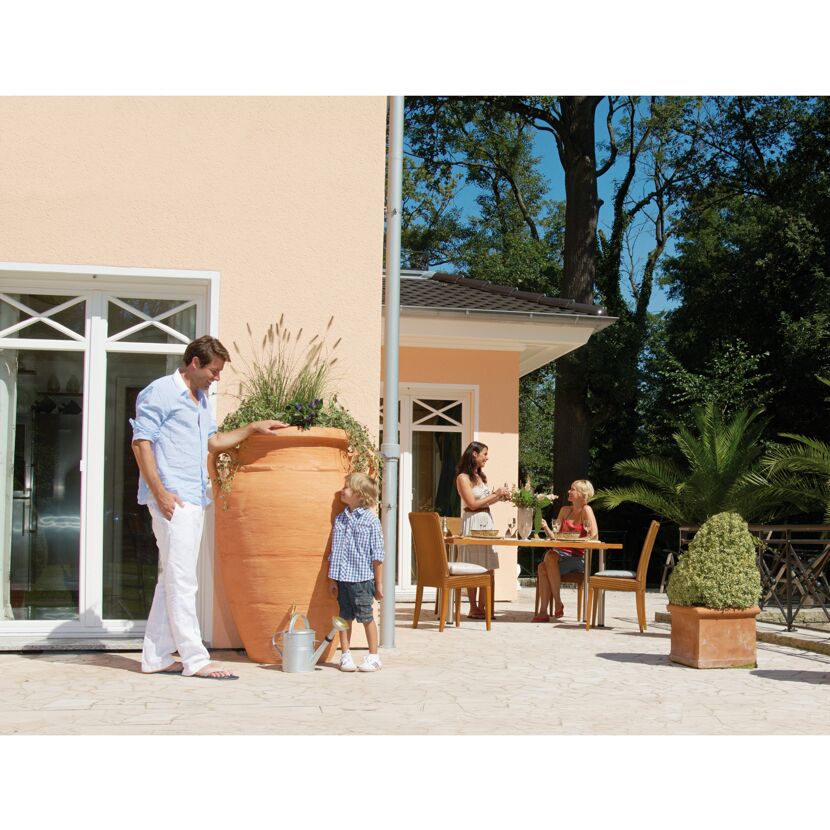 Familie entspannt auf der Terrasse am Haus mit Regentonne
