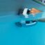 Person reinigt einen Pool mit einer Bürste.
