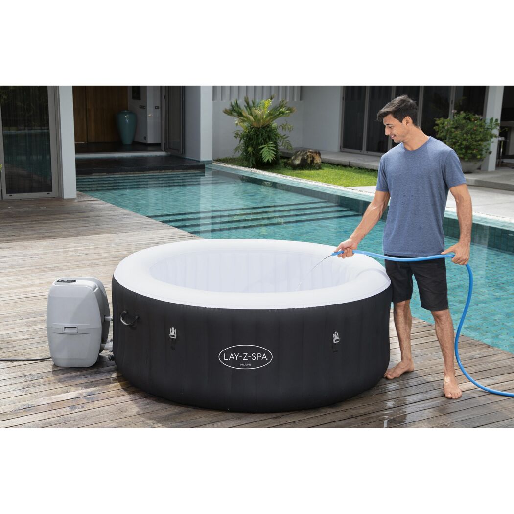 Person füllt einen Lay-Z-Spa Whirlpool mit einem Gartenschlauch.
