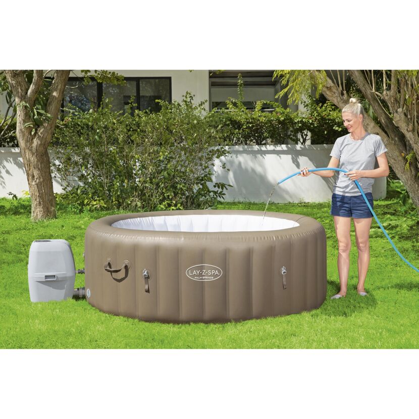 Person füllt einen Lay-Z-Spa Whirlpool mit einem Gartenschlauch.