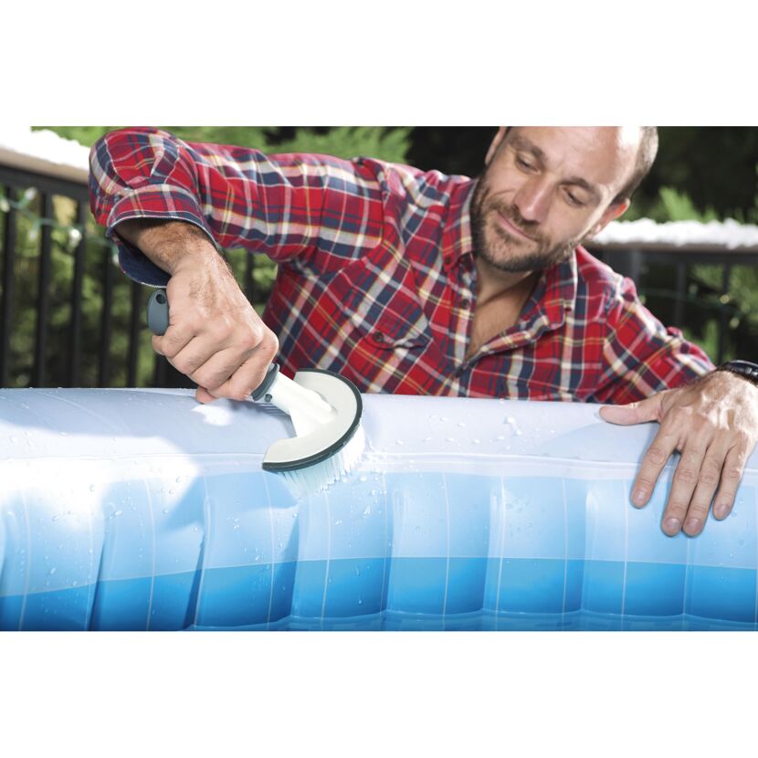 Person reinigt einen aufblasbaren Whirlpool mit einer Bürste.
