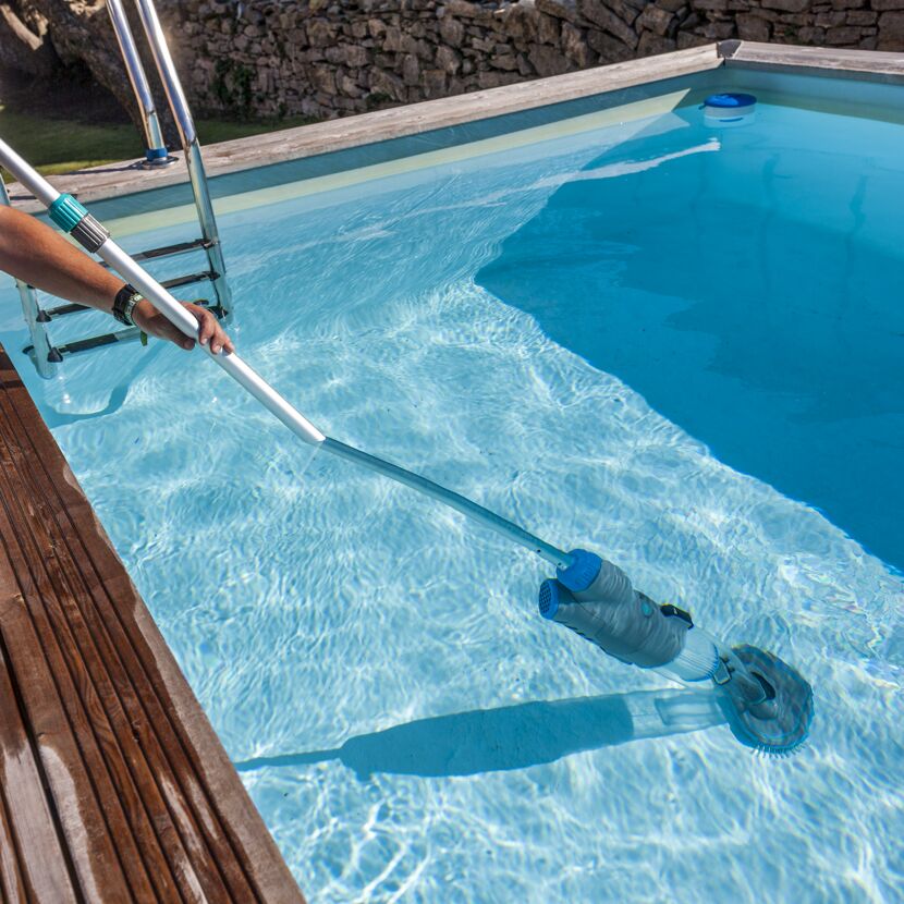 Person reinigt einen Pool mit einem Poolsauger.