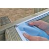 Person befestigt blaue Poolfolie an Holzrahmen