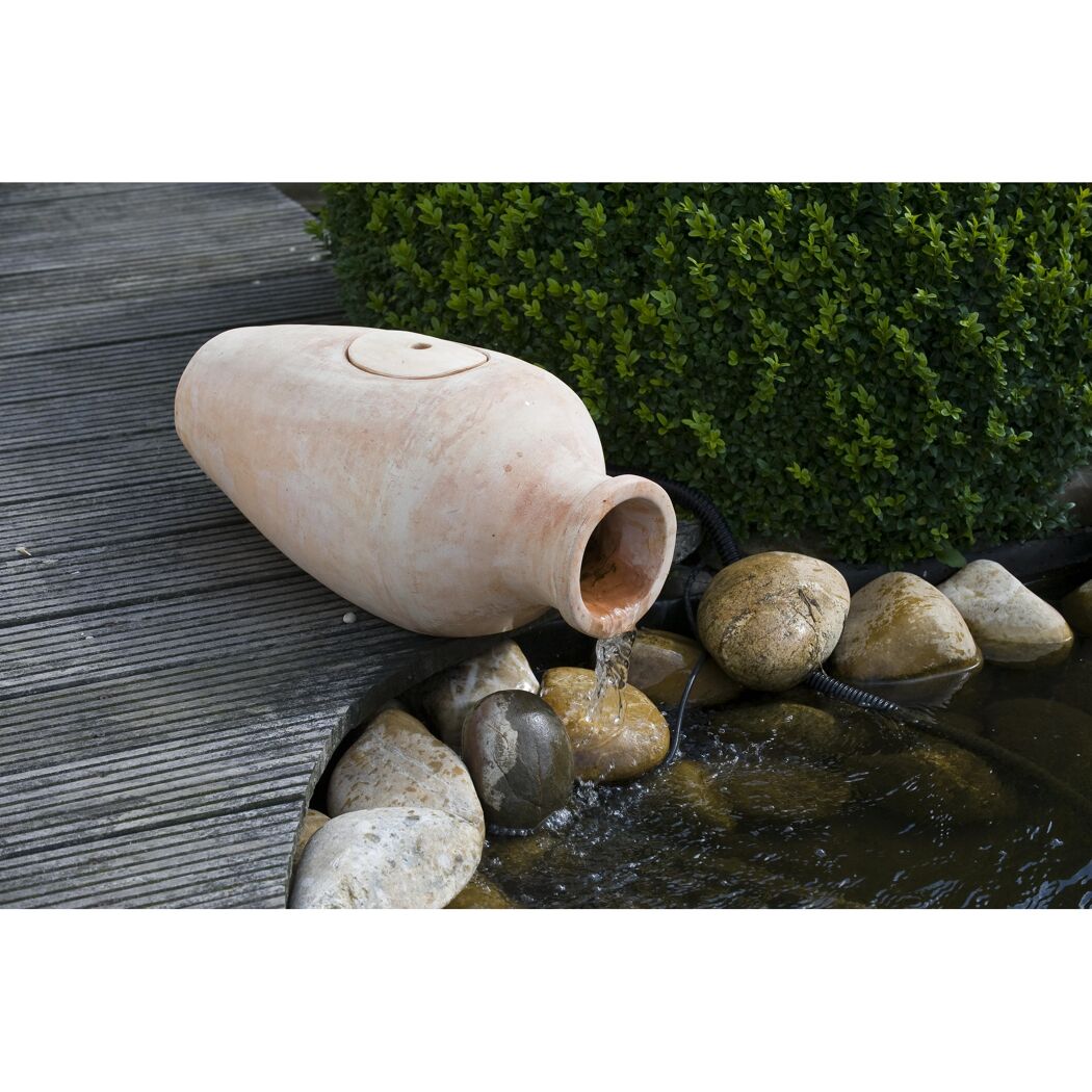 Wasser fließt aus einem Krug in einen Teich.