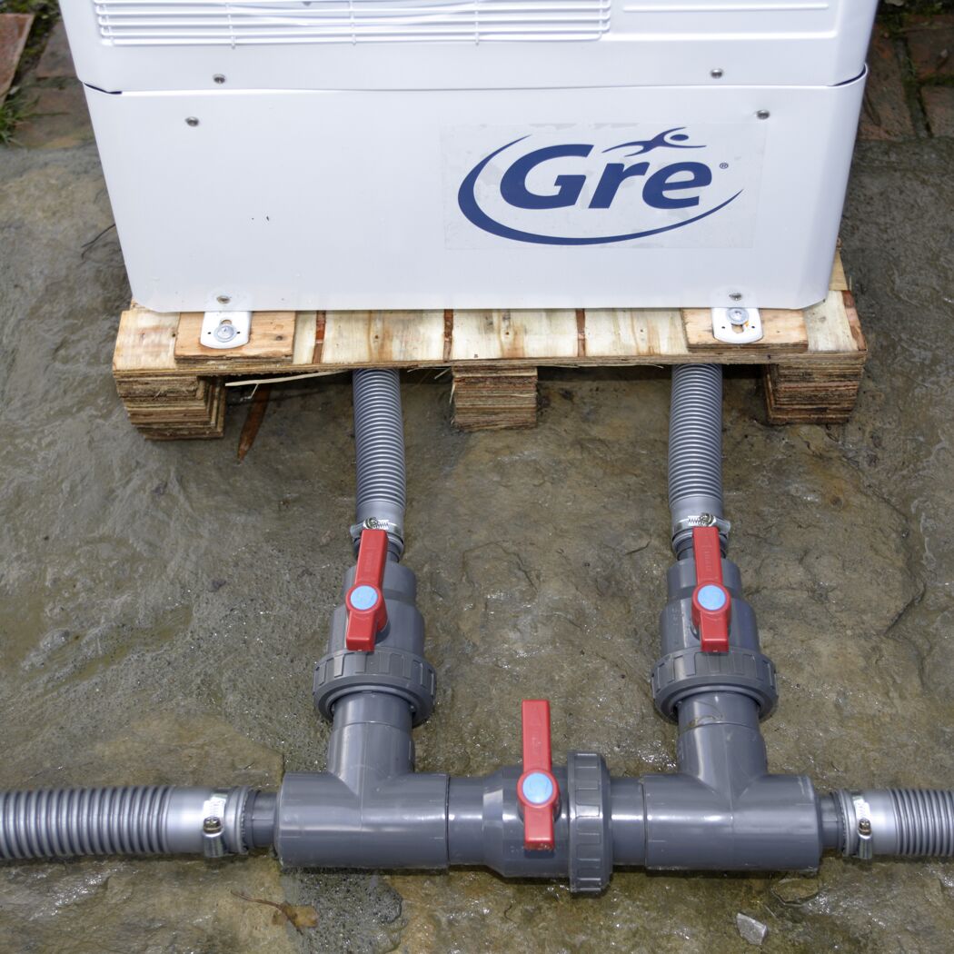 Wärmepumpe von Gre auf Palette mit angeschlossenen Rohren und Ventilen.