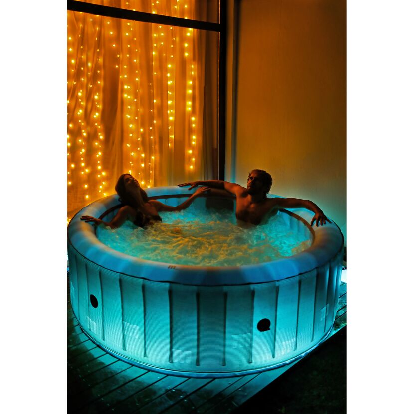 Zwei Personen entspannen in einem beleuchteten Whirlpool.