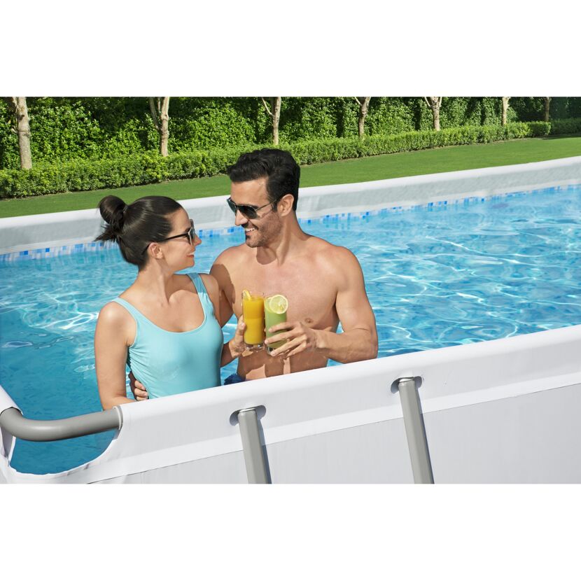 Zwei Personen stoßen mit Gläsern im Pool an.