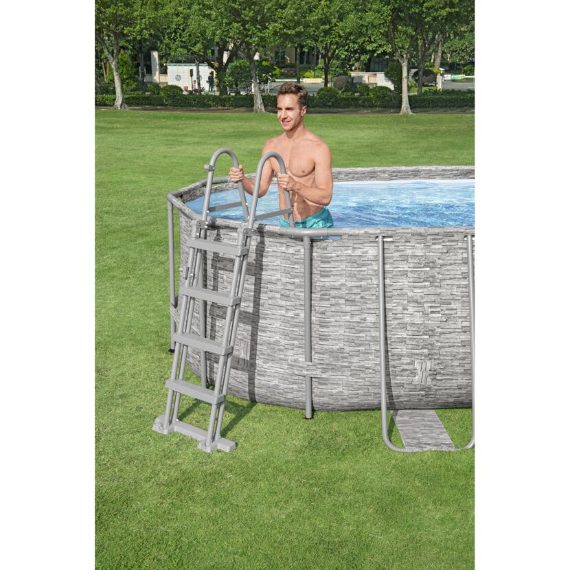 Person steigt in einen Aufstellpool mit Poolleiter.