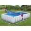 Zwei Personen decken einen rechteckigen Pool mit einer blauen Solar-Poolabdeckung ab.