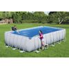 Zwei Personen am rechteckigen Aufstellpool mit Solar-Poolabdeckung