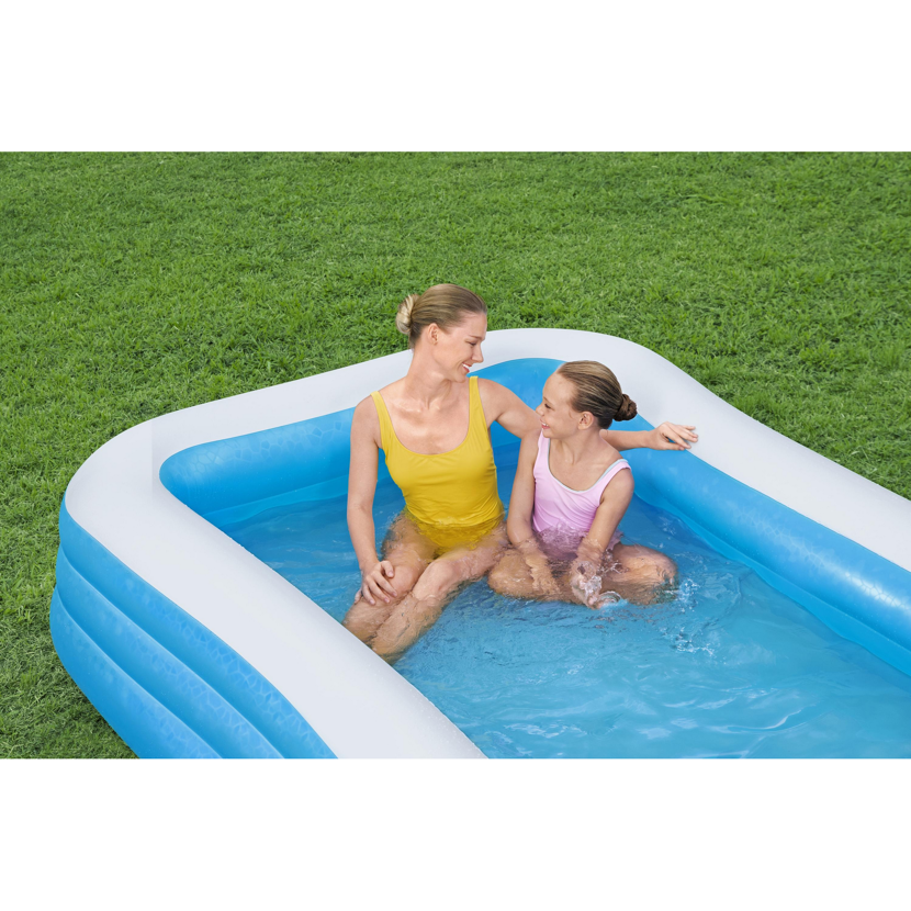 Erwachsene Person und Kind sitzen in einem blauen Familienpool.