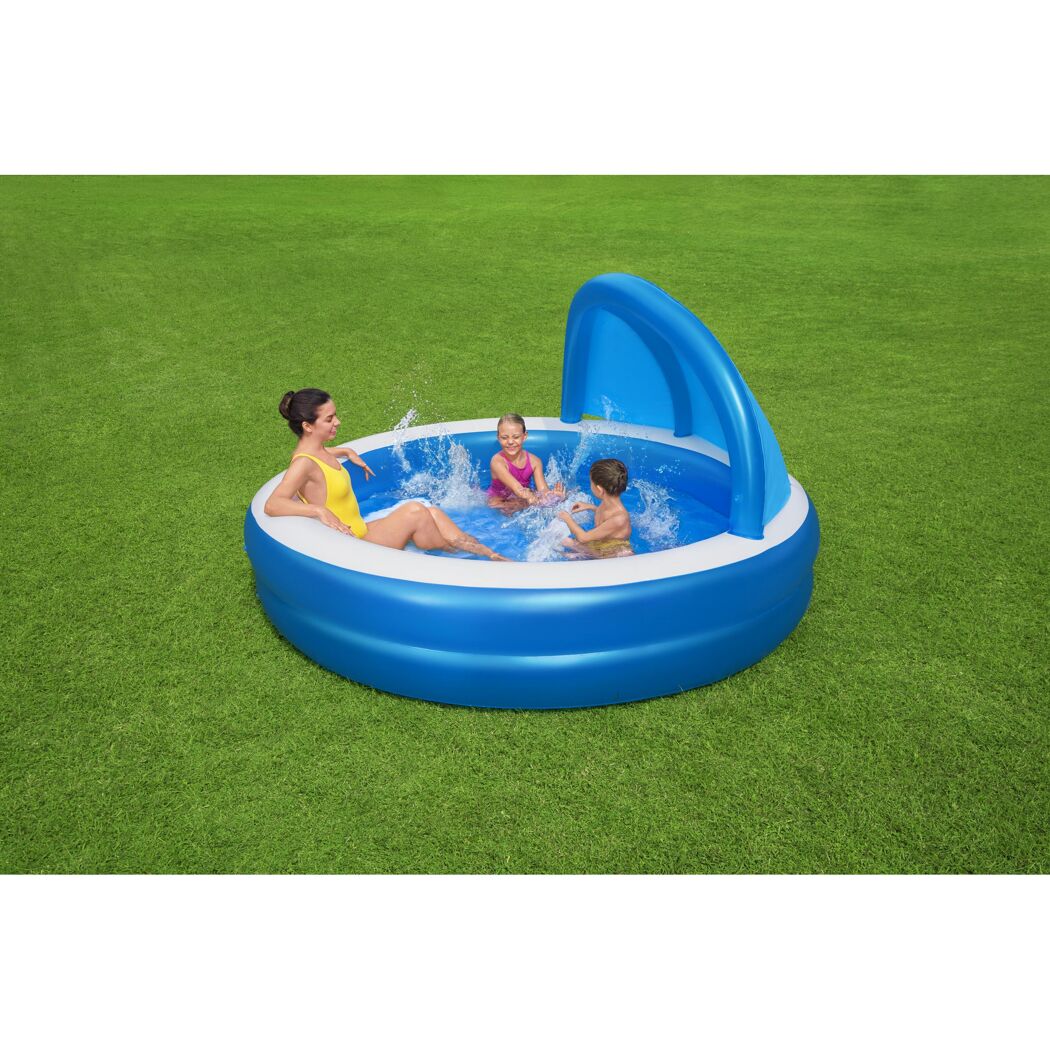 Eine Person und zwei Kinder planschen in einem blauen Family Pool mit Sonnenschutz.