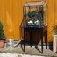 Kleines Gewächshaus mit Pflanzen auf einem Holzboden