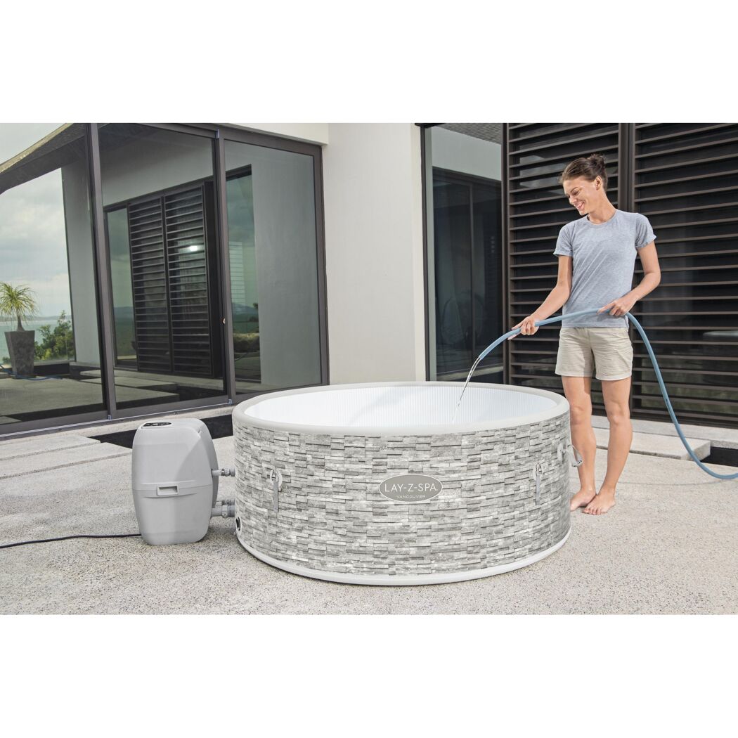 Person füllt einen Lay-Z-Spa Whirlpool mit einem Schlauch.
