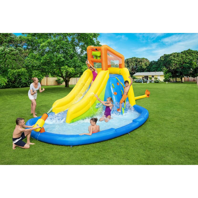 Kinder spielen in einem aufblasbaren Wasserpark mit Rutsche.