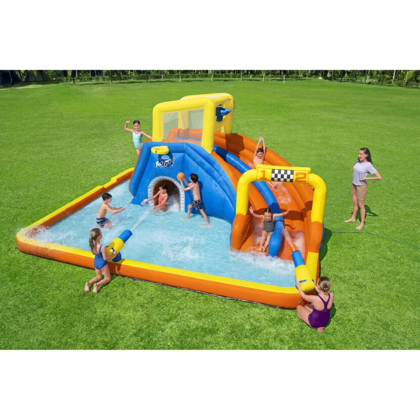 Kinder spielen in einem aufblasbaren Wasserpark mit Rutschen.