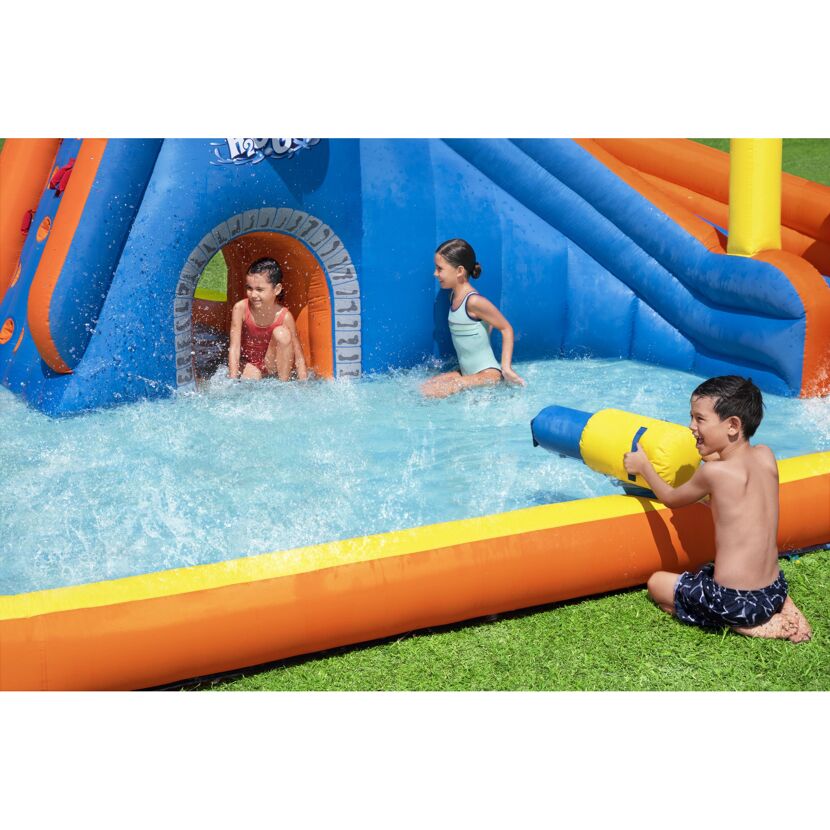 Drei Kinder spielen in einem aufblasbaren Wasserpark.
