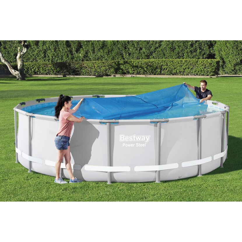Zwei Personen decken einen aufblasbaren Pool mit einer blauen Solarabdeckplane ab.
