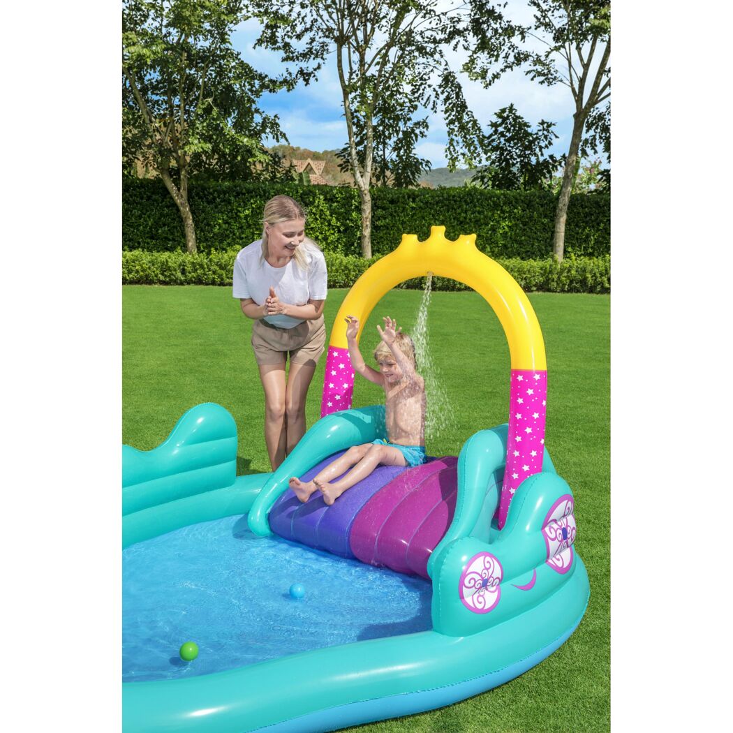 Kind rutscht im Planschbecken mit Rutsche und Wasserfontäne