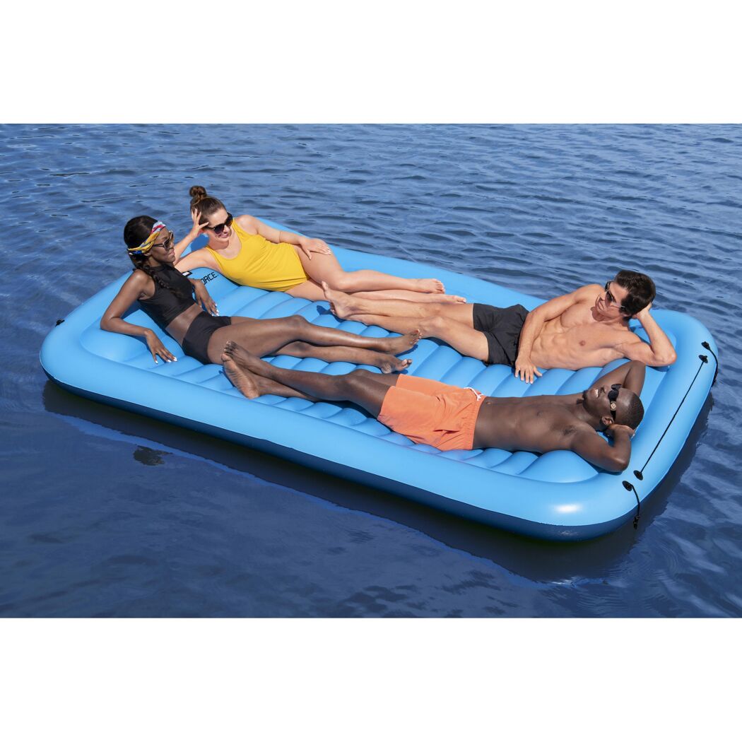 Vier Personen entspannen auf einer blauen aufblasbaren Schwimm-Plattform.
