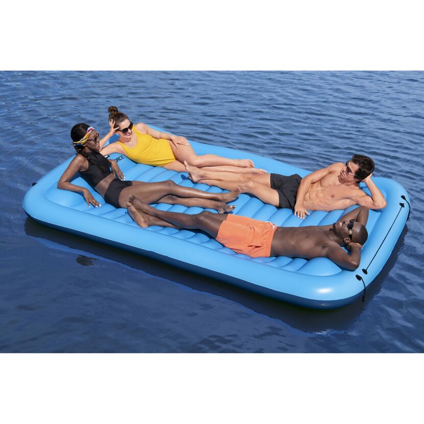 Vier Personen entspannen auf einer blauen aufblasbaren Schwimm-Plattform.