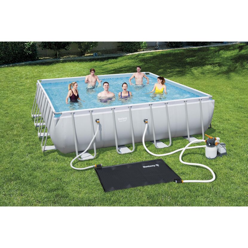 Mehrere Personen in einem rechteckigen Pool im Garten. Daneben liegt eine Solarheizmatte und eine Filterpumpe.