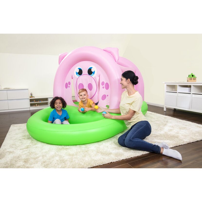 Drei Kinder spielen in einer aufblasbaren Hüpfburg in Form eines Schweins.