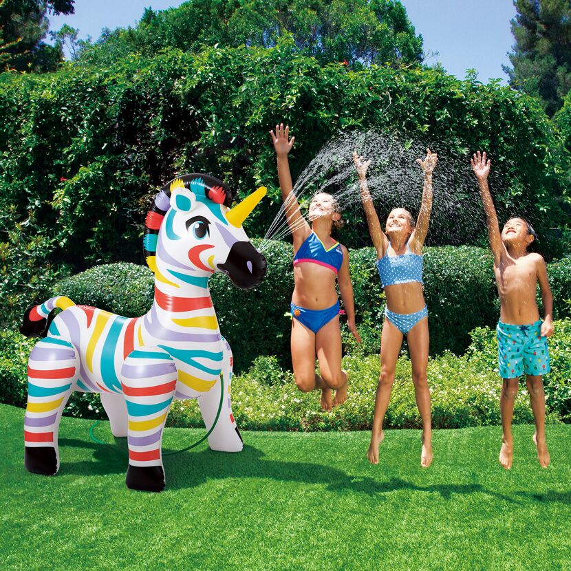 Drei Kinder spielen mit einem aufblasbaren Zebra-Sprinkler.