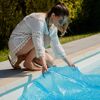 Person bedeckt Pool mit Solarplane