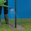 Person gießt mit grüner Gießkanne Ruck-Zuck-Beton an Zaunpfosten