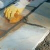 Person verlegt Natursteinplatten mit Schwamm und Mörtel