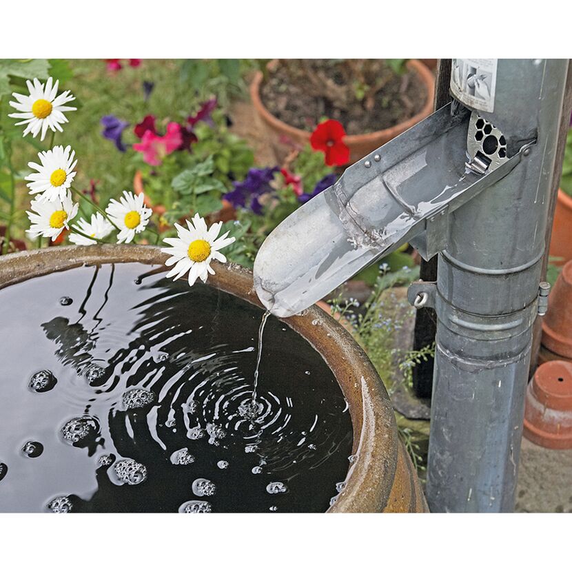 Regenwasser fließt aus einem Fallrohr in ein Regenfass.