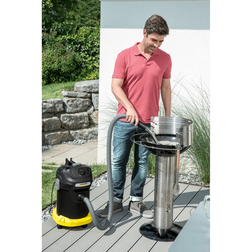 Person saugt Asche aus einem Grill mit einem Aschesauger.