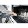 Person saugt Asche mit einem Aschesauger aus einem Kamin.