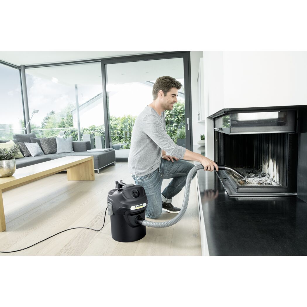 Person saugt Asche mit einem Kärcher Aschesauger aus einem Kamin.