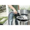 Person saugt Asche mit einem Aschesauger aus einem Grill.