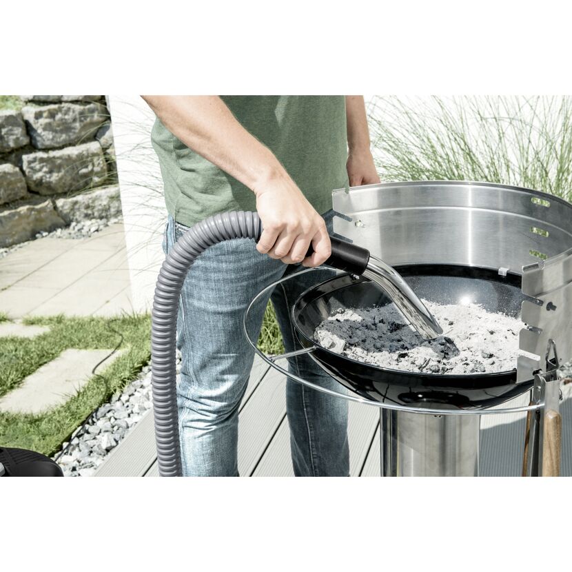 Person saugt Asche mit einem Aschesauger aus einem Grill.