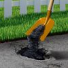 Asphalt wird mit einer Schaufel in ein Loch gefüllt.